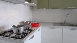 Een moderne keuken met witte kasten, een gasfornuis en roestvrijstalen kookgerei.