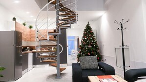 Eine moderne Küche mit Wendeltreppe, einem Essbereich mit Weihnachtsbaum und einem Kleiderständer.