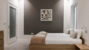 Ein modernes Schlafzimmer mit einem hölzernen Bett, einem Nachttisch, einem Wandbild und einer Tür mit Milchglas.