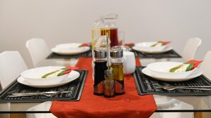 Ein Esstisch ist mit Tellern, Besteck und Gewürzen gedeckt.