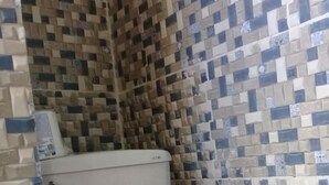 A bathroom with a white toilet, a pink seat cover with a red flower design, and a tiled wall with a checkered pattern. - Villa Julirous Rd, spa and Aparthotel Camp for Vacationers (Boca Chica)