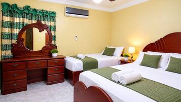 Ein Hotelzimmer mit zwei Betten, einem Holzschrank, einem Spiegel, einer Klimaanlage und einem Deckenventilator.