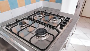 A kitchen with a gas stove, a sink, and a tiled backsplash. - Poolside Getaway-beahost (Rosolina)