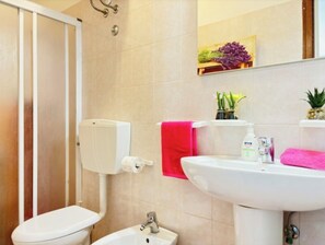 A bathroom with a toilet, bidet, sink, and a mirror.