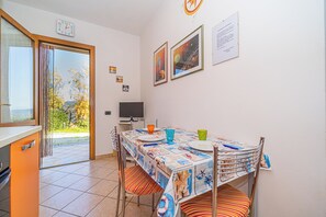 A dining area with a table set for two, a television, and a window with curtains.