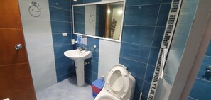 A bathroom with a white sink, blue-tiled walls, a mirror, and a toilet. - Edificio Sea View - San Andres Island (San Andrés)