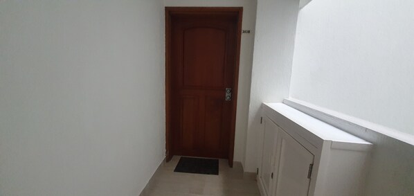 A narrow hallway with a wooden door and a white radiator on the right.