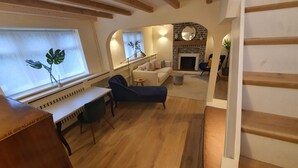 Een moderne woonkamer met een bank, een bureau en een open haard.