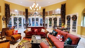 A spacious living room with a red sofa, a wooden coffee table, and a chandelier. - 6br 6ba Luxury Villa is Perfect for Your Vacation! (Davenport)