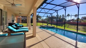 A covered outdoor area with a pool, lounge chairs, and a view of the surrounding landscape. - 6br 6ba Luxury Villa is Perfect for Your Vacation! (Davenport)