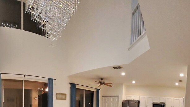 A modern living room with a white sectional sofa, a fluffy rug, and a chandelier. - 6br 6ba Luxury Villa is Perfect for Your Vacation! (Davenport)