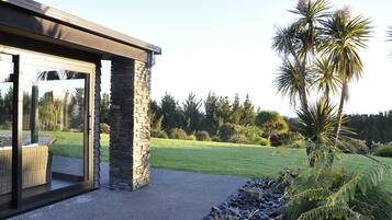 A modern building with a stone exterior, large glass doors, and a view of a well-maintained lawn and trees.