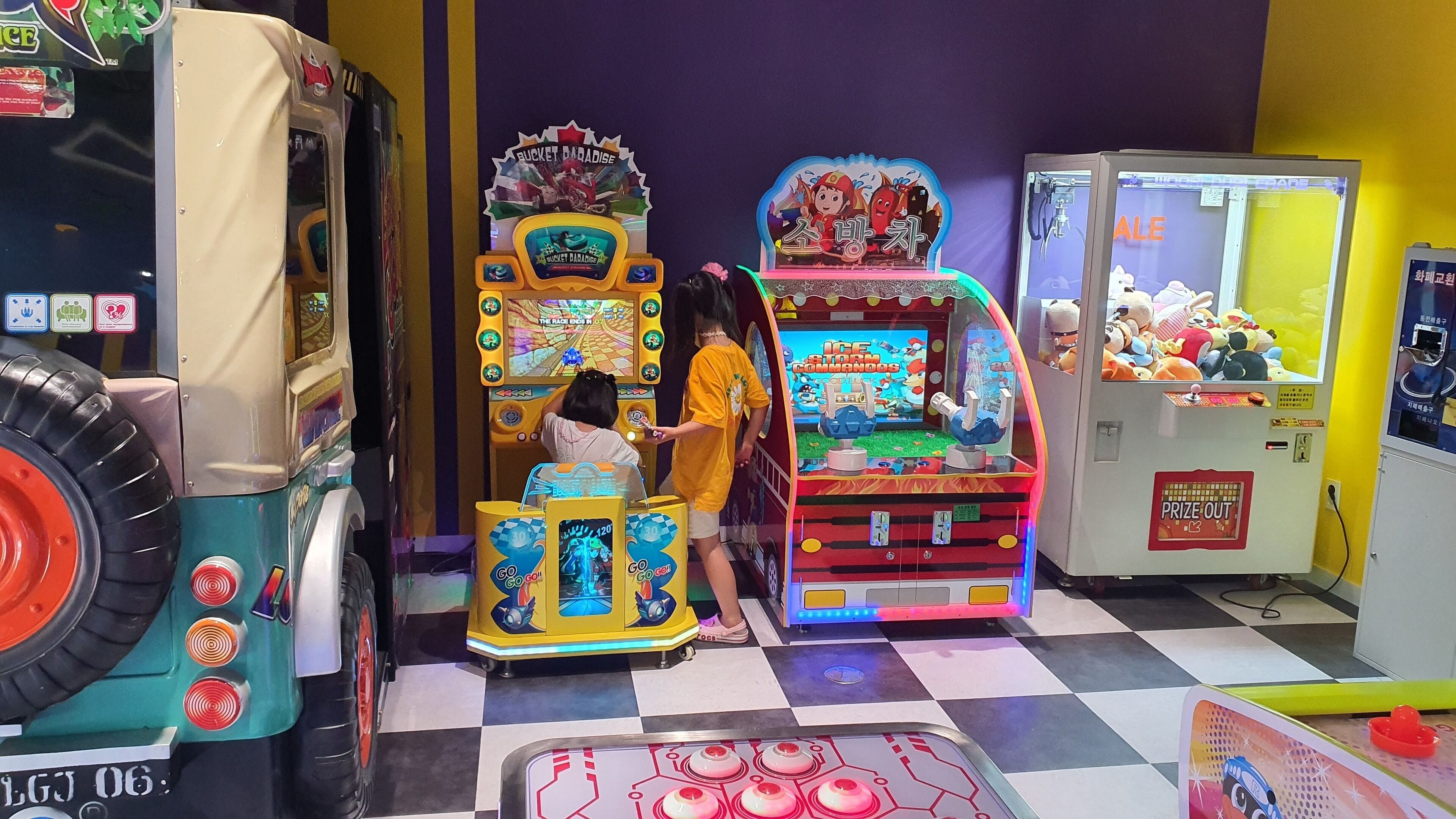En rad med färgglada spelautomater står uppradade i ett rum med ett rutmönstrat golv.