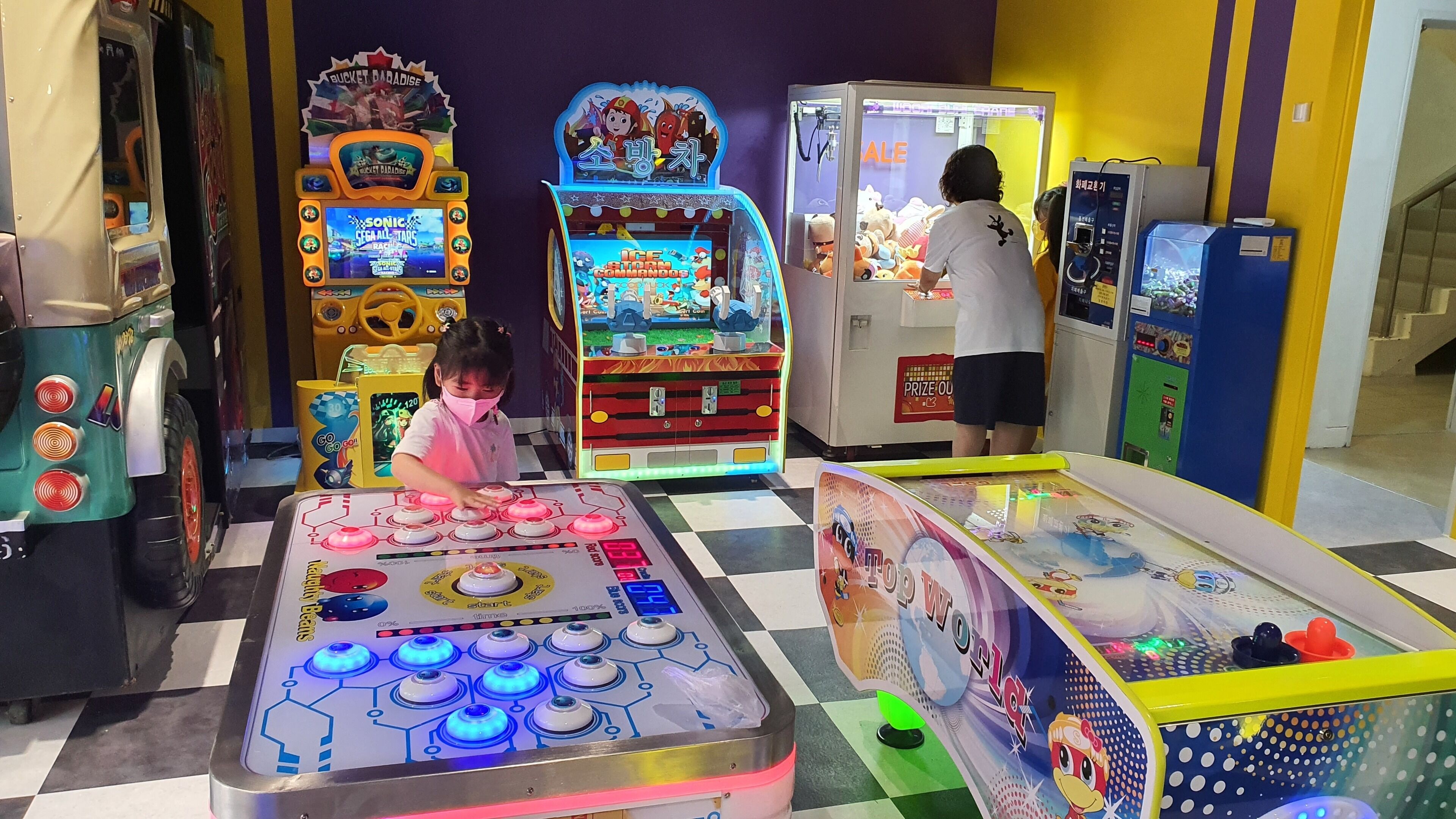 Variedad de juegos de arcade y una máquina con garra en un espacio interior bien iluminado.