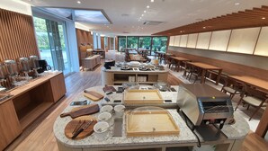 Un moderno comedor para desayunos con barra libre, muebles de madera y amplias ventanas que ofrecen vistas al exterior.