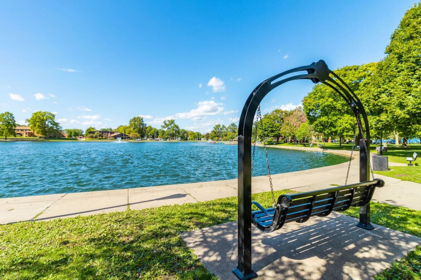 Un parque con un columpio y un banco junto a un lago.