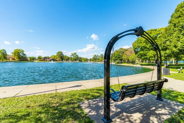 A park with a swing set and a bench by a lake. - #306 Pekin · Pekin Pie à la Mode #306 (Pekin)