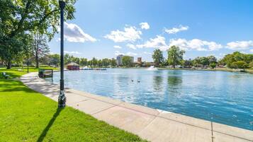 A park with a calm water body, a walking path, and a lamp post.