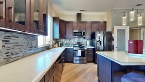 Una cocina moderna con armarios de madera oscura, electrodomésticos de acero inoxidable y salpicadero de azulejos.