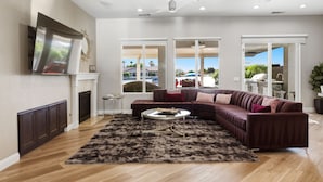 Amplia sala de estar con sofá modular, chimenea y ventanas grandes que ofrecen vistas al exterior.