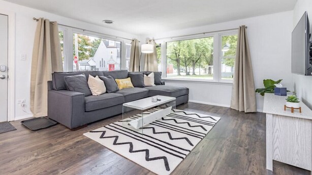Una sala de estar moderna con un sofá gris, una mesa de centro y una alfombra estampada.