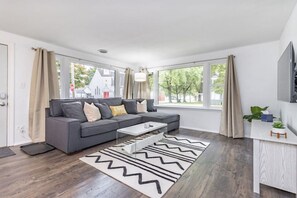 Una sala de estar moderna con un sofá gris, una mesa de centro y una alfombra estampada.