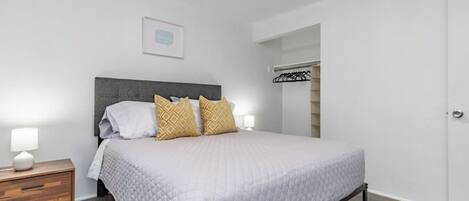 A bedroom with a bed, bedside tables, and a wardrobe.