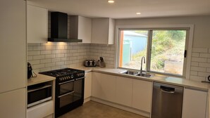Eine moderne Küche mit weißen Schränken, einem Gasherd, einem Backofen, einer Mikrowelle, einem Toaster und einem Geschirrspüler.