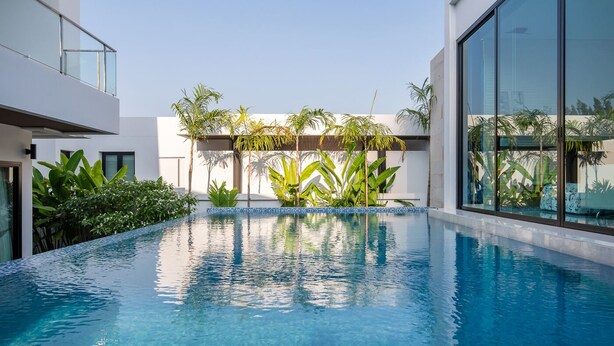 Uma piscina moderna com água azul cristalina, rodeada por vegetação exuberante e arquitetura contemporânea.
