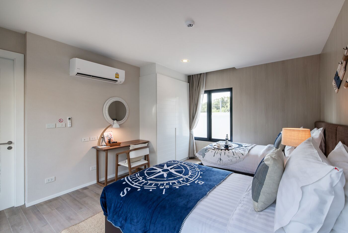 A bedroom with a bed, desk, chair, and an air conditioning unit.