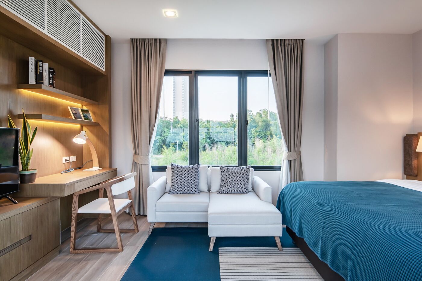 Una habitación de hotel moderna con escritorio, sofá y cama.