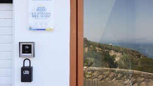 Letrero de una casa de huéspedes con datos de contacto y vista al paisaje costero a través de una ventana.