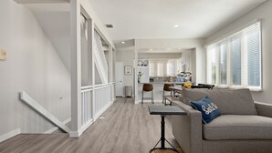A modern living room with a grey sofa, a coffee table, and a staircase leading to another level. - ⚓The Tree House! Beautiful townhome in Longboat Key with great amenities surrounded by nature!⚓ (Longboat Key)