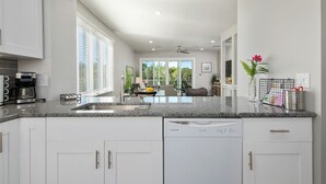 A modern kitchen with white cabinetry, a built-in dishwasher, and a granite countertop. - ⚓The Tree House! Beautiful townhome in Longboat Key with great amenities surrounded by nature!⚓ (Longboat Key)