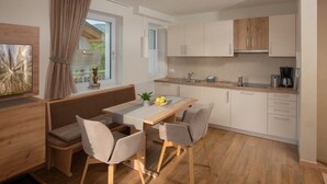 A modern kitchen with a dining area, wooden cabinets, and a view of the outdoors. - Vacation apartment Bruneck, ideal for bikers & hikers, garage, Cron 4 sauna & pool (Brunico)