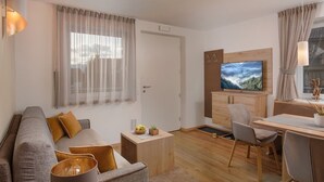 A modern living room with a sofa, coffee table, and a TV mounted on a wooden cabinet. - Vacation apartment Bruneck, ideal for bikers & hikers, garage, Cron 4 sauna & pool (Brunico)