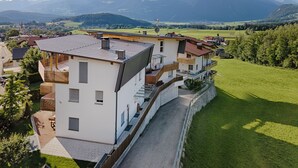 A modern multi-story building with a sloped roof, a covered outdoor area, and a view of a mountainous landscape. - Vacation apartment Bruneck, ideal for bikers & hikers, garage, Cron 4 sauna & pool (Brunico)
