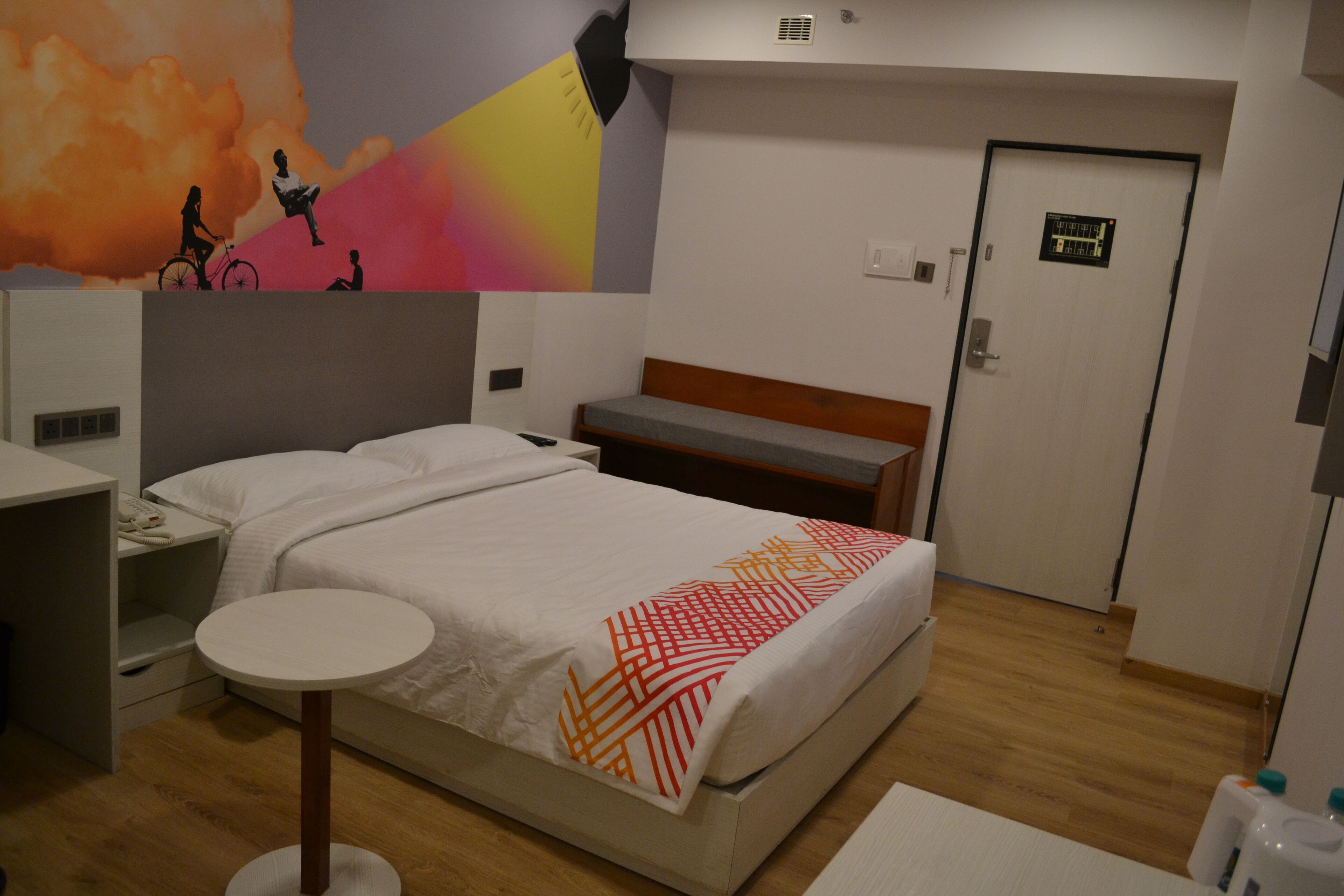 A hotel room with a bed, bedside table, and a small round table.