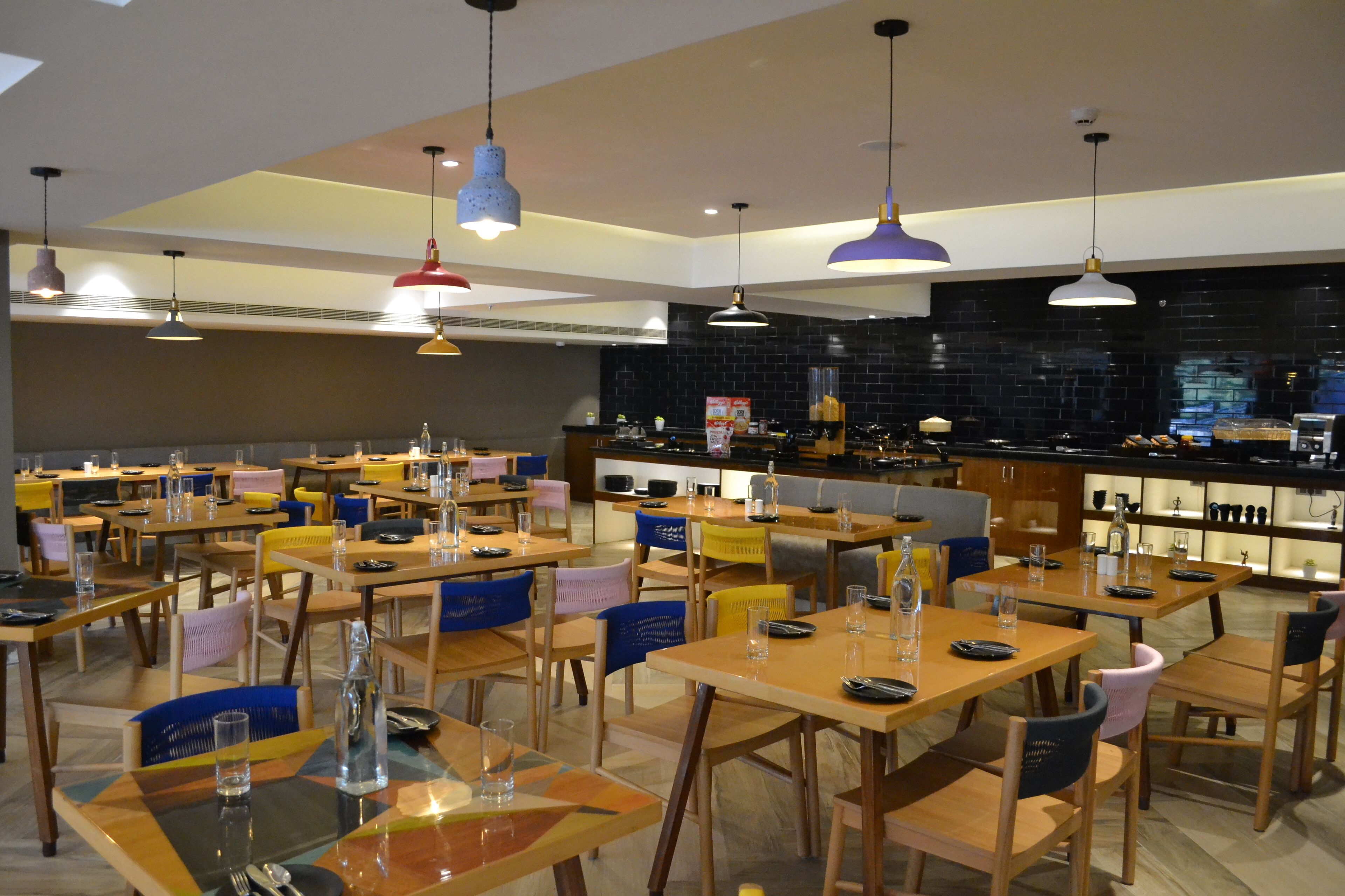 A restaurant with multiple tables and chairs, a bar area, and pendant lighting.