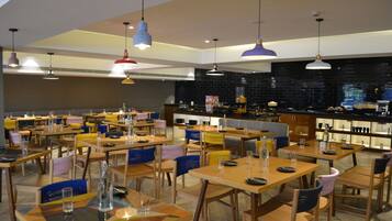A restaurant with multiple tables and chairs, a bar area, and pendant lighting.
