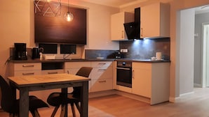 A compact kitchen with a dining table, chairs, a coffee maker, and a microwave.