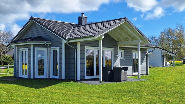 Een laag huis met een puntige dakschild, een overdekte veranda en een schoorsteen.