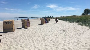 Een strand met rieten stoelen en een rij strandhutten.