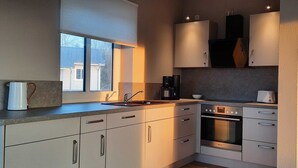 Een moderne keuken met een inbouwoven, een koffiezetapparaat en een waterkoker op het aanrecht.