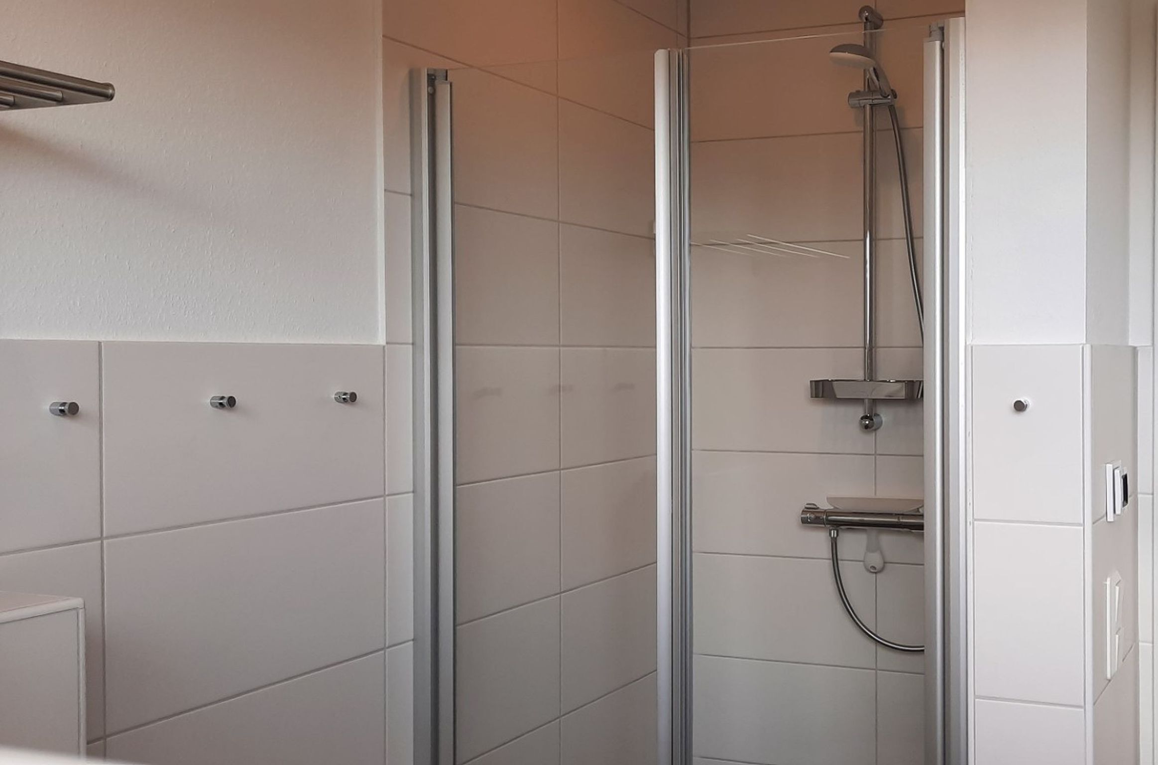 Een moderne badkamer met een douchecabine van glas, witte betegelde wanden en een minimalistisch design.