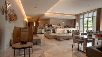 A spacious, modern living area with a large kitchen in the background, featuring a dining table and comfortable seating.