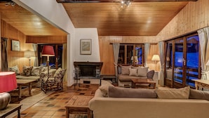 Una sala de estar acogedora con chimenea, techo de madera y ventanas amplias.