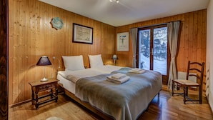 Una habitación con paneles de madera, una cama grande, dos mesitas de noche y una silla.