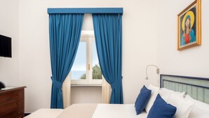 A bedroom with a bed, blue curtains, a window with a view, a painting on the wall, and a bedside lamp. - I giardini dell'Eden, Pool Amalfi Villa, jacuzzi, stunning view, garden, parking (Amalfi)