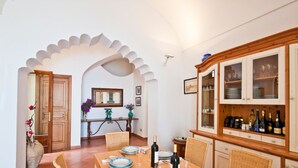 A dining area with a table set for four, a cabinet with glass doors, and a mirror above the table. - Mille e una notte Luxury Villa With Stunning Sea View and private pool (Conca dei Marini)